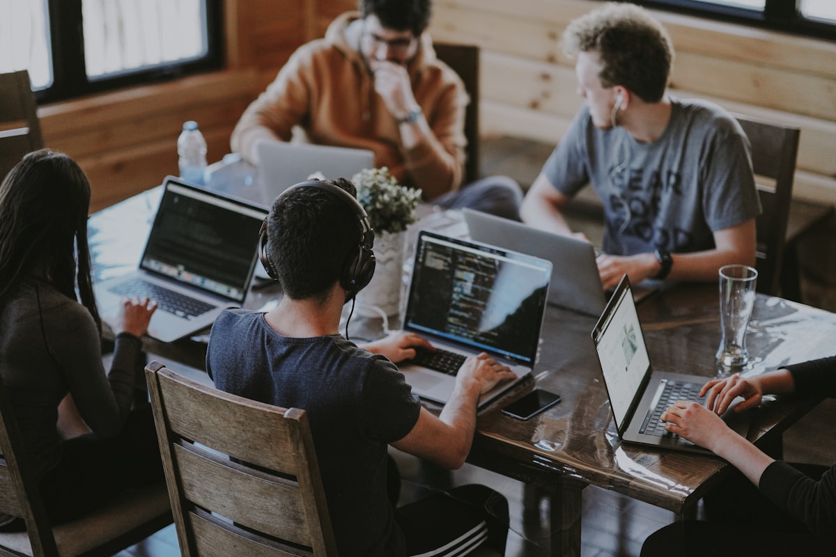 Diverse digital marketing agency team collaborating over laptop screens in a modern tech office
